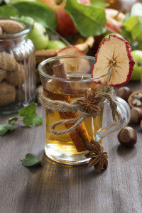 apple cider with spices in a glass cup, vertical